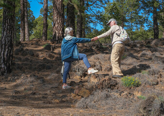 Elderly carefree couple hiking in outdoors mountain excursion enjoying healthy lifestyle in...