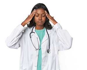 Young Indian doctor with stethoscope touching temples and having headache.