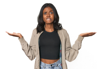 Portrait of a young Indian woman confused and doubtful shrugging shoulders to hold a copy space.