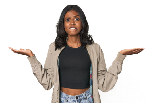 Portrait of a young Indian woman confused and doubtful shrugging shoulders to hold a copy space.