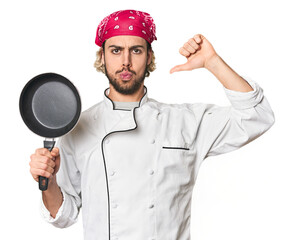 Naklejka premium Young Caucasian male chef with frying pan feels proud and self confident, example to follow.