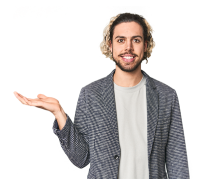 Young businessman in casual blazer showing a copy space on a palm and holding another hand on waist.