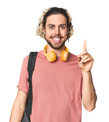 Young student with backpack and headphones showing number one with finger.