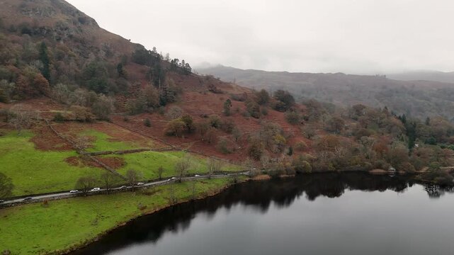 Rydal Water, A scenic aerial view of a road winding through a vibrant green landscape, framed by a calm lake and rolling hills.