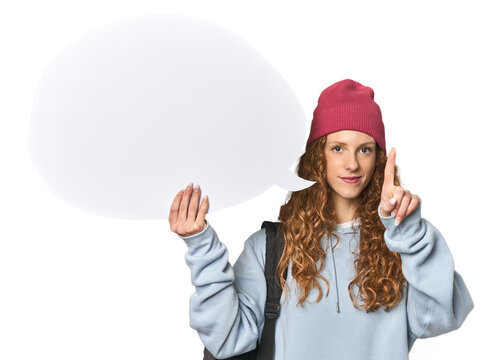 Redhead holding a comic speech bubble showing number one with finger.
