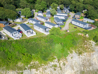 UAV view of summer holiday mobile homes seen on the cliff edge of rural Suffolk, UK. The cliff is...
