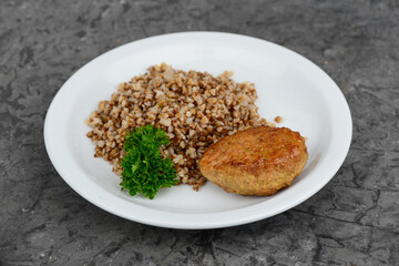 buckwheat porridge with cutlet in a white plate