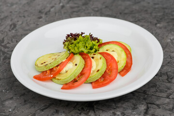 zucchini salad with tomatoes and cheese in a white plate macro photo