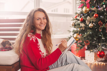 Woman writing shopping list, Christmas letter or wish list