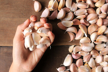 Hand Holding garlic cloves on wooden table background