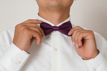 Groom Adjusting Purple Bow Tie On Wedding Day