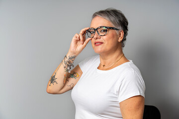 Confident spanish woman adjusting glasses and showing tattoos