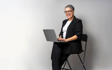 Smiling senior businesswoman working on laptop in studio
