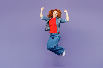 Full body young ginger woman she wearing red t-shirt denim shirt jump high doing winner gesture...