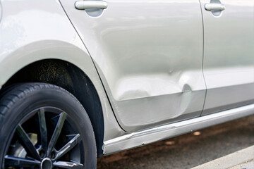 Close view of dented car door with bodywork damage and deformed surface showing repair issue after...