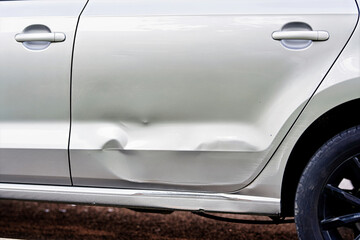 Car bodywork damage with severe dent and paint defect on side door closeup of vehicle after crash showing repair problem and need for automotive service