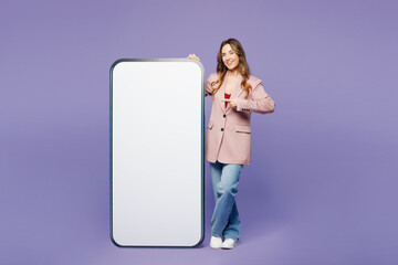 Full body young woman wear beige jacket formal clothes point finger on big huge blank screen mobile...
