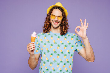 Young happy man wear blue beach t-shirt yellow hat sunglasses rest near hotel pool eat vanilla...