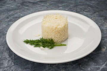 white rice in a white plate with greens on a gray concrete background