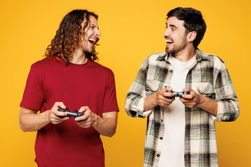 Young smiling two friends buddies men they wear casual clothes together hold in hand play pc game...