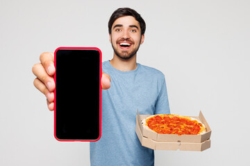 Young man wear blue casual clothes hold pizza in cardboard flatbox use blank screen mobile cell...