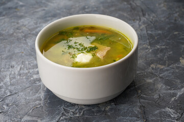 soup with greens in a white plate on a gray background