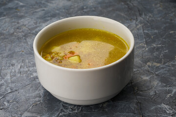 Pea soup with herbs in a white plate on a gray concrete background