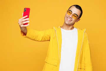 Young middle eastern man wear raincoat casual clothes sunglasses do selfie shot on mobile cell...