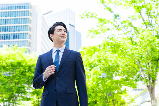 Male business person walking through the green city