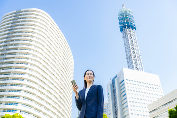 街でスマホを使う女性ビジネスパーソン