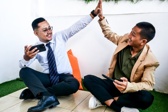 Two Businessmen Exchange A Cheerful High Five While Playing Games