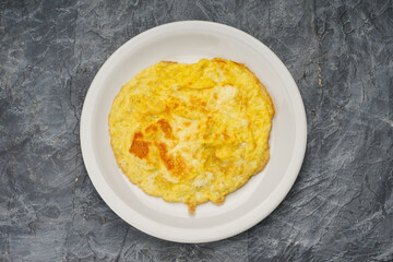 egg omelette in a white plate on a gray concrete background