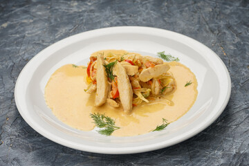 chicken in tomato sauce in a white plate on a gray concrete background