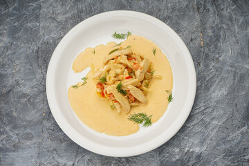 chicken in tomato sauce in a white plate on a gray background