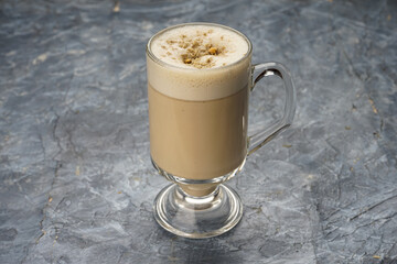 Cappuccino in a transparent cup on a gray background