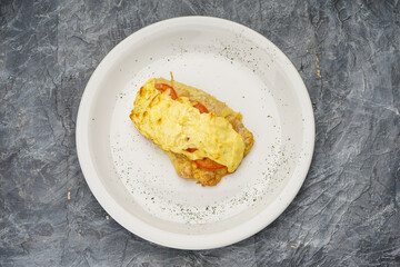 chicken chop with tomato and cheese in a white plate on a gray background