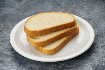 three slices of white bread in a white plate on a gray background