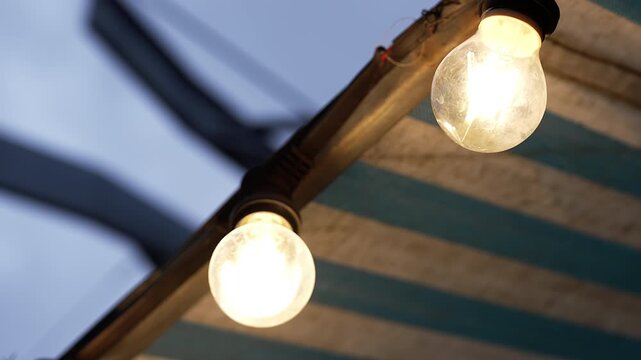 Warm glowing light bulbs hanging in outdoor patio with bokeh
