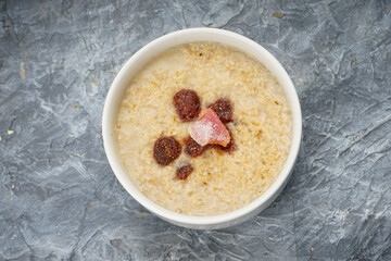 Oatmeal with milk in a white plate on a gray background