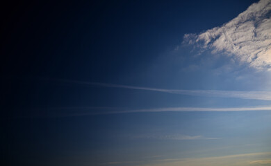 Engine exhaust contrails in the blue cloudy sky.