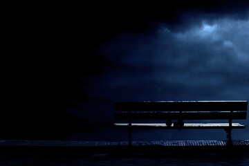 Empty park bench under a stormy night sky