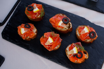Delicious salmon bites with lemon and olives served on a slate platter at a summer outdoor gathering