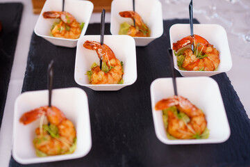 Delicious shrimp appetizers arranged on a black slate during a vibrant outdoor gathering in the afternoon sun