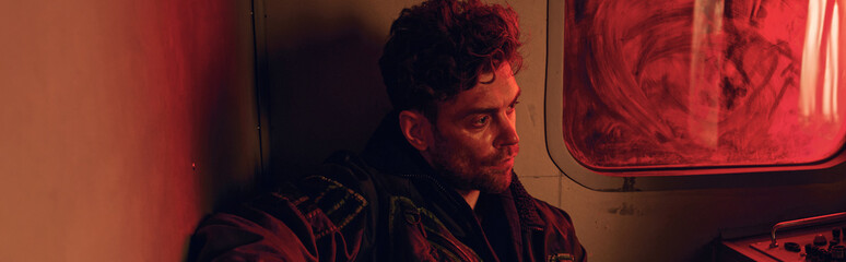 In a dimly lit room, a young man reflects on his existence amid the remnants of a lost world.