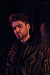 Obraz premium A young man stands confidently in a desolate environment, exuding strength and grit amidst chaos.