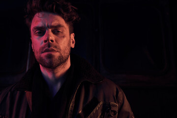 A young man stands with resolve, surrounded by the remnants of a dystopian landscape at twilight.