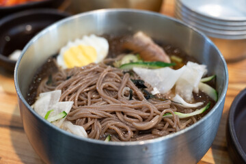 Korean Naengmyeon Cold Noodles with Egg and Vegetables in Chilled Broth.