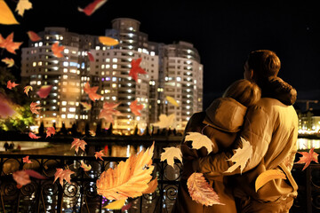 A couple in love hugs on a romantic night walk against the backdrop of a large new house