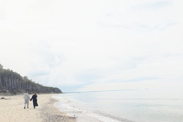 man and woman, couple in love on the seashore spring or autumn view seasonal photo in warm clothes