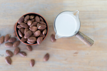 Fresh milk in a glass and almond nuts in a mini bowl on a wooden table. Healthy food and drink...